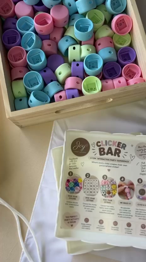 Wooden tray of pastel clicker buttons in mint, blush, sky blue and lilac