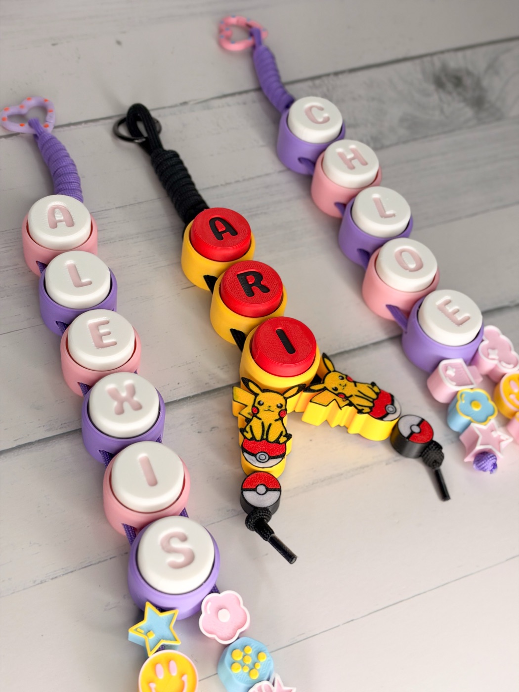 Three finished clicker keyrings spelling Alexis, Ari and Chloe, each with different colours and charms